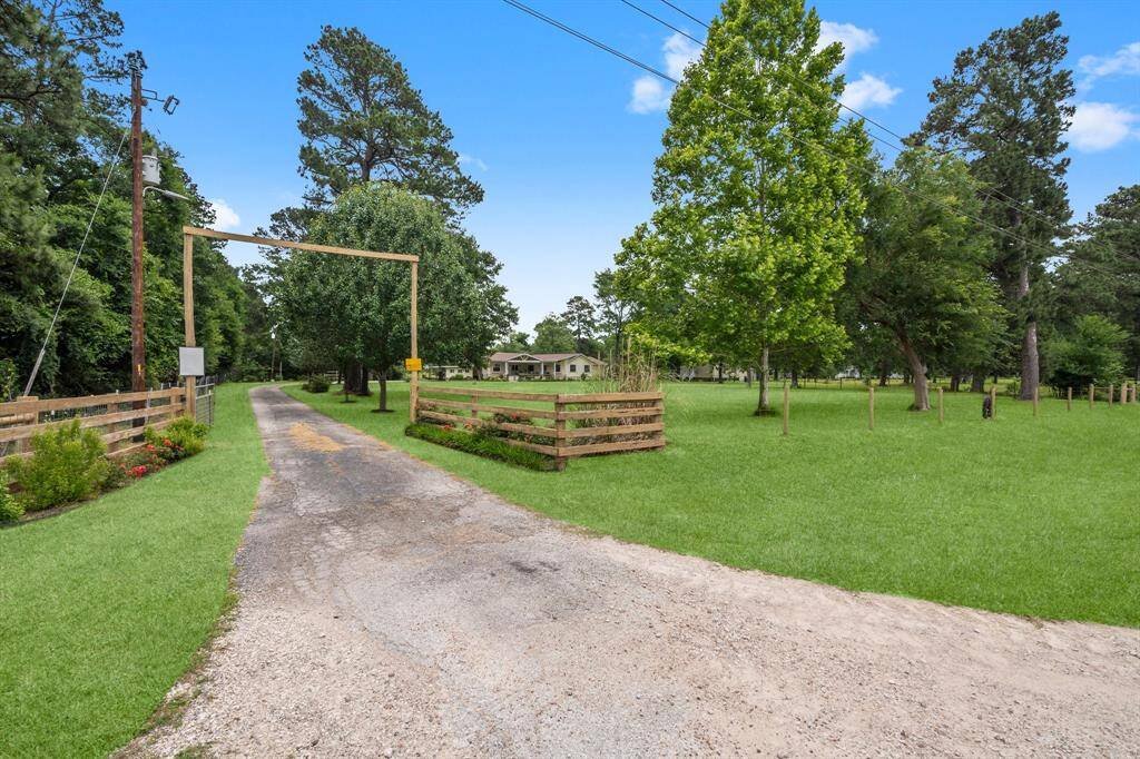 A scenic rural property with a long driveway leading up to the home, surrounded by lush green grass and mature trees, offering a peaceful and private setting.