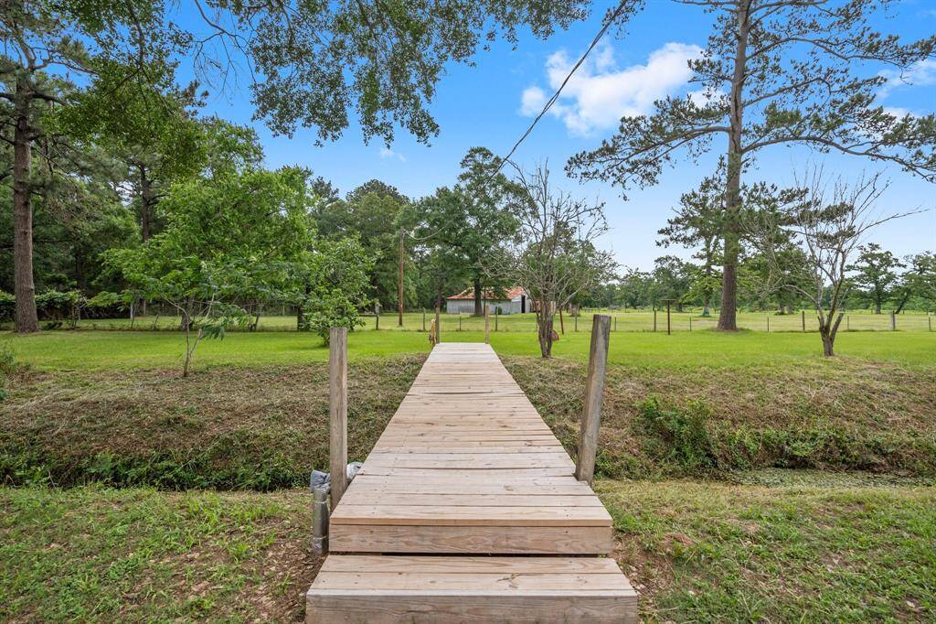 A charming wooden walkway over the wet-weather creek leads to the pastures, pond and barn in the rear of the property.