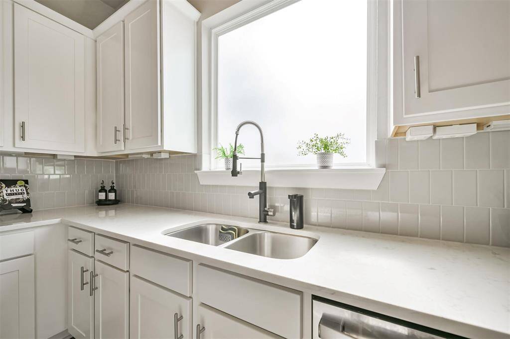 Stylish subway tile backsplash, stainless steel sink, and a picture window overlooking the outdoors.