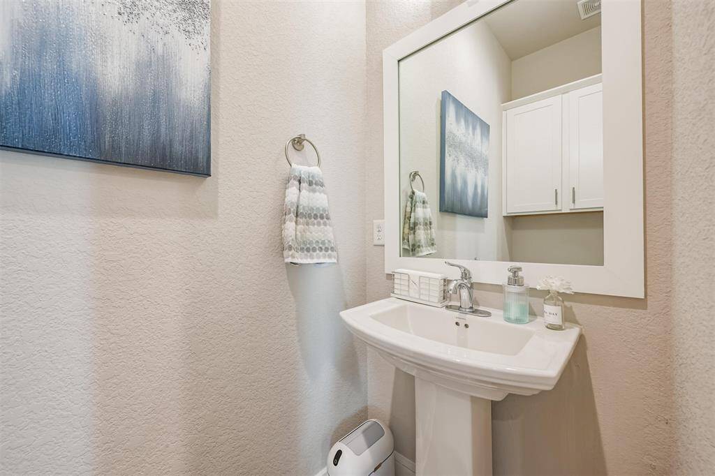 Well-maintained half-bath with a pedestal sink, large mirror and built-in medicine cabinet.