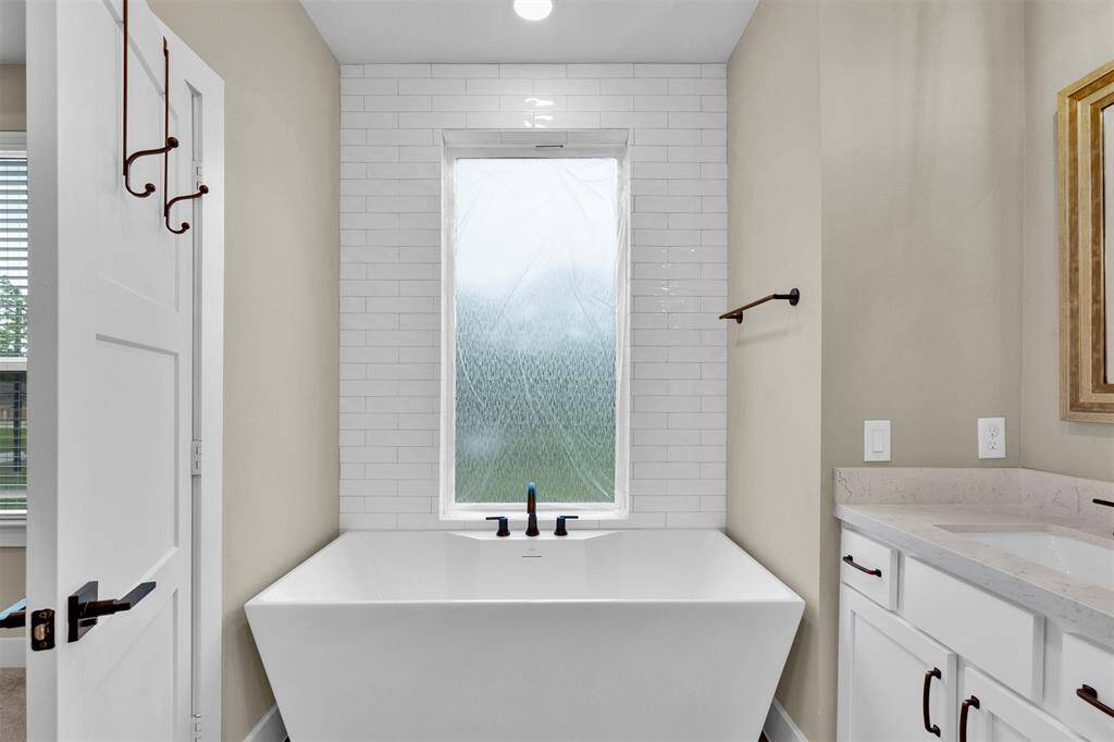 Single soaking tub within the primary bath with an elegant tiled wall.
