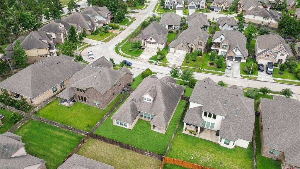 This aerial photo shows a suburban neighborhood with well-maintained homes, each featuring spacious yards and driveways. The streets are lined with trees, and the area appears peaceful and residential, ideal for family living.