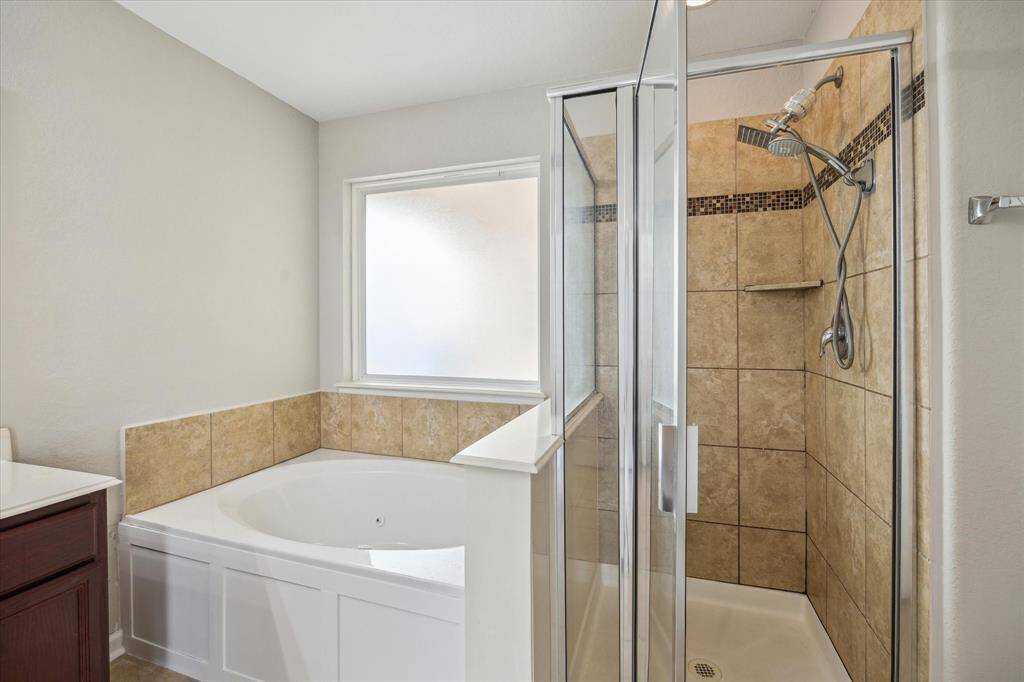 The bathroom features an upgraded design with a separate bathtub and walk-in shower