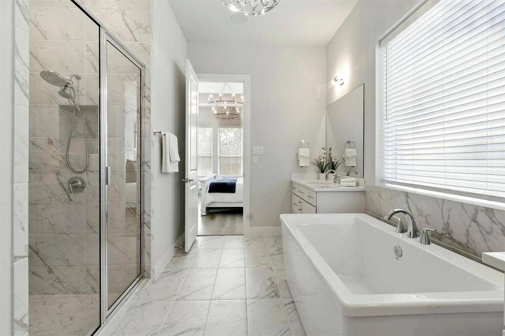 Bright bedroom with large windows, white furniture, and modern decor. Features a cozy bed with blue accents and stylish lighting, creating an inviting and serene atmosphere.