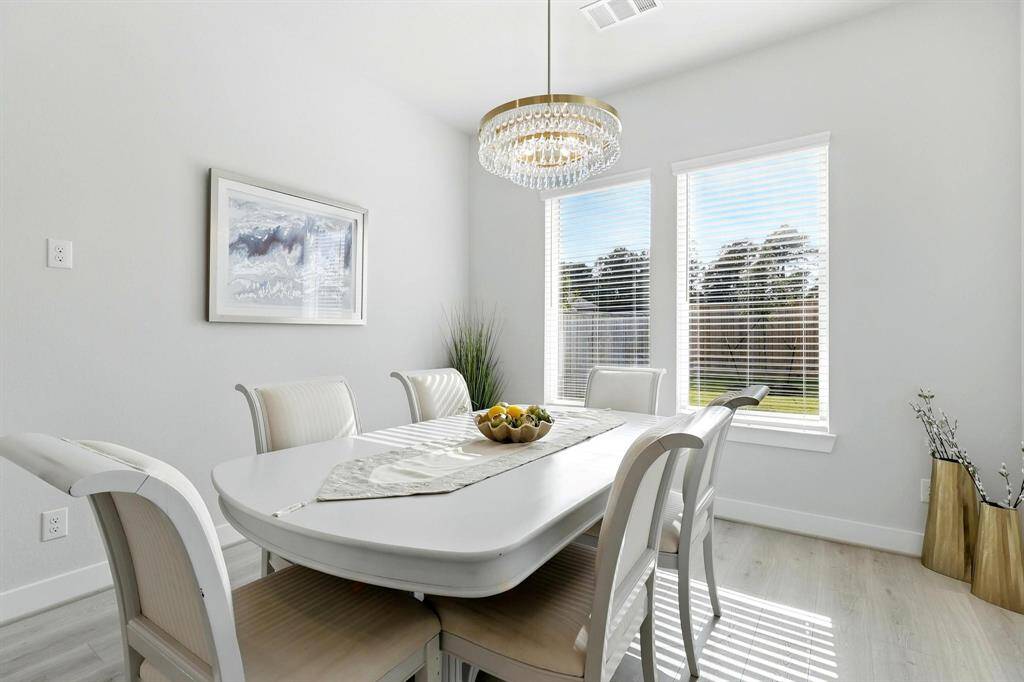 This modern two-story home with a spacious backyard. The exterior features light brickwork and large windows, and there's a covered patio area perfect for outdoor relaxation. The yard is enclosed by a wooden fence, providing privacy and security.