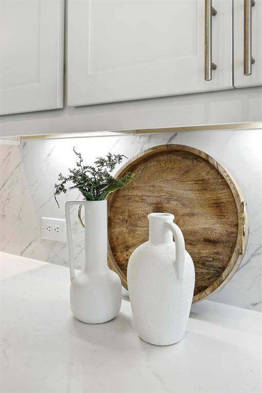 A stylish, well-organized primary walk-in closet with white shelving and drawers, featuring ample storage for handbags and accessories, plus hanging space for clothing.