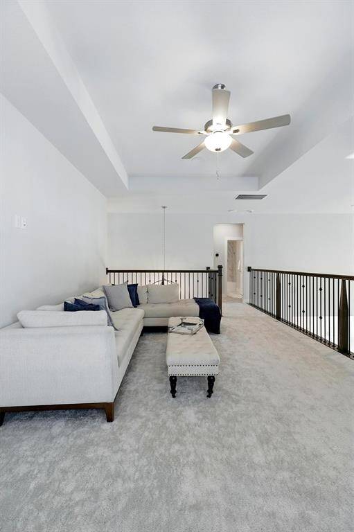 This modern kitchen features a spacious island with a sleek white countertop and gold fixtures. It includes stainless steel appliances, a wine fridge, and ample cabinetry. Adjacent is a cozy living area with a contemporary fireplace, and an elegant staircase enhances the open-concept design. Perfect for entertaining.