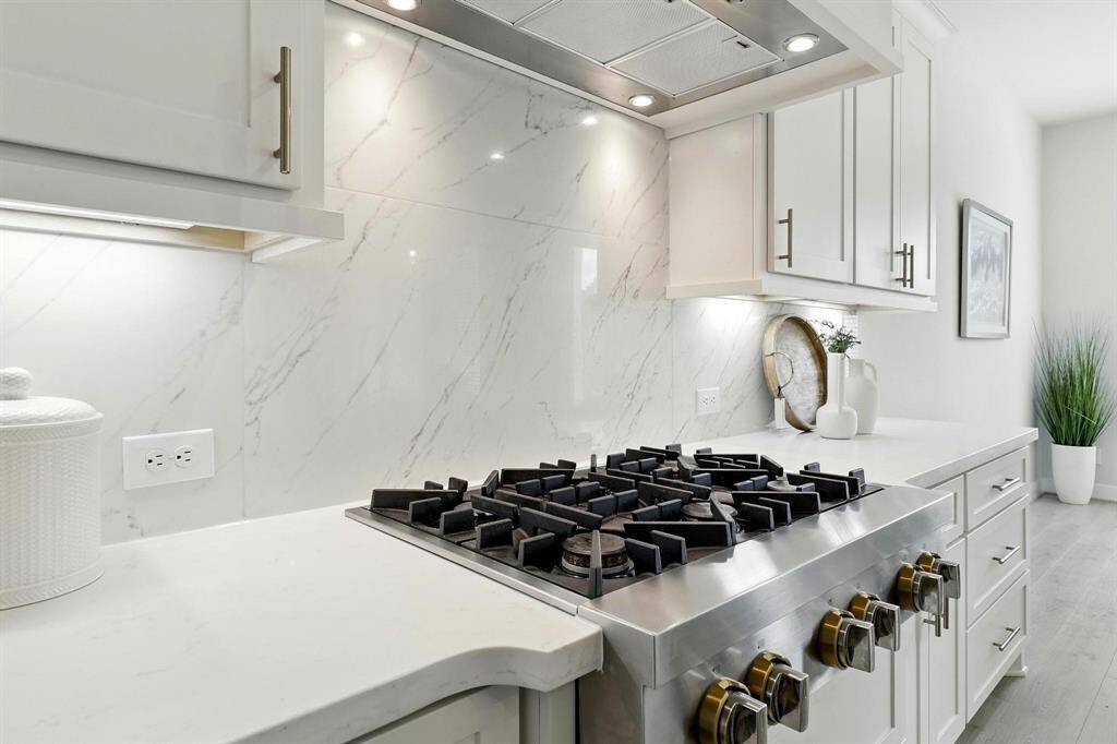 Modern kitchen with gas upgraded cooktop , white cabinetry, gorgeous backsplash, and quartz countertops, creating a clean and elegant look.