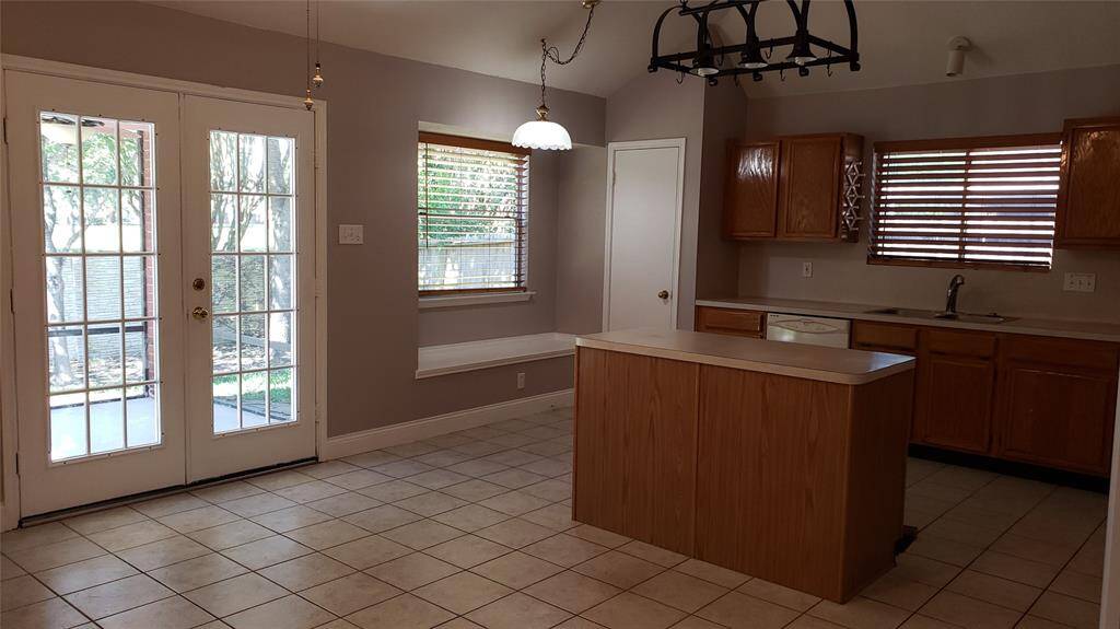 Island kitchen with view of french doors leading to the covered patio in the back yard and the window seat. There is so much natural light in this room! Countertops are now granite.