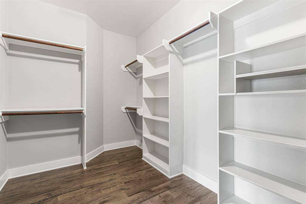 Spacious walk-in closet attached to the primary bathroom with ample shelving and hanging space, featuring  a clean, modern design. Ideal for organizing clothes and accessories.