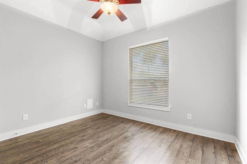 This bedroom features a ceiling fan and a window with blinds, offering a cozy and modern space.