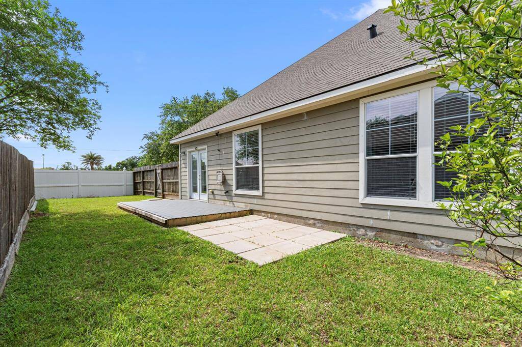 Charming backyard with a small deck and patio area, surrounded by a wooden fence for privacy. Ideal for outdoor relaxation and entertaining.