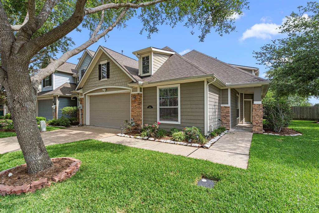 Charming home with a well-maintained lawn, mature trees, and a welcoming front entrance. Features a two-car garage, brick accents, and a cozy porch.