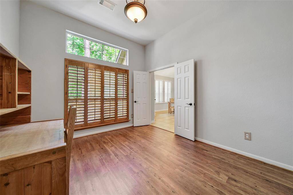 Plantation shutters, wood floors, and a high ceiling create an elegant and enjoyable work space.