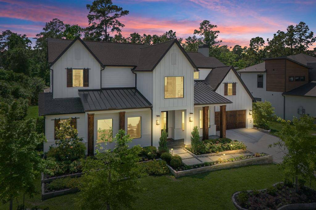 Twilight curb appeal! This stunning modern farmhouse glows at dusk, highlighting its architectural lines, elevated front porch, and beautifully landscaped corner lot. The warm lighting, gabled rooflines, and black-trimmed windows create an unforgettable first impression—perfectly capturing the home’s elegant curb appeal.