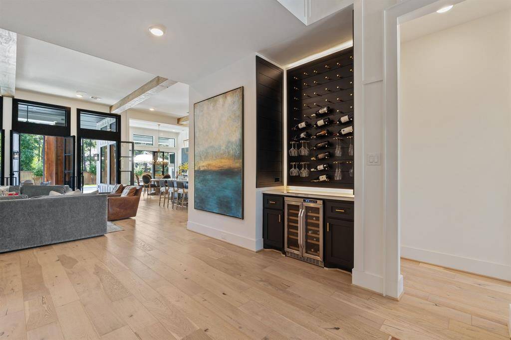 This show stopping custom wine bar display features backlit shelving, a built-in wine fridge, and space for both bottles and stemware—perfectly positioned between the living and dining areas. A sophisticated yet functional focal point for effortless entertaining.