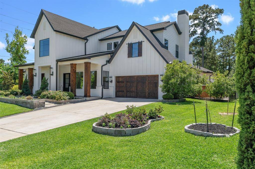 This side-angle perspective highlights the home’s impressive depth, architectural detail, and oversized driveway leading to a charming wood-accented garage. The manicured landscaping and covered porch add warmth and welcome to this modern farmhouse’s stately curb presence.