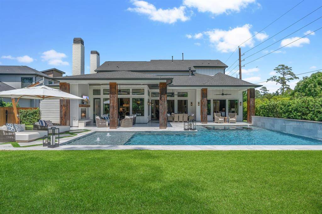 The expansive covered patio, outdoor fireplace, and sleek pool create the perfect setting for entertaining or unwinding