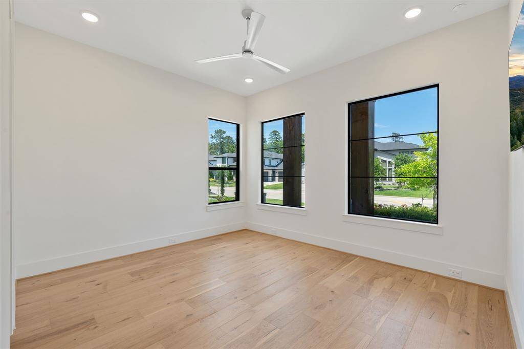 This spacious secondary bedroom offers wide-plank hardwood floors, designer windows with black trim, and an abundance of natural light. A peaceful corner retreat—ideal as a guest room, nursery, or secondary office with a view.