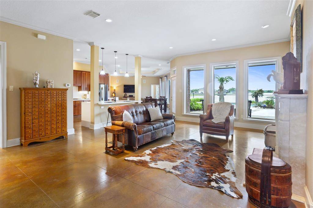 The open-concept living area showcases stunning floor-to-ceiling windows that offer breathtaking views of the lake and pool. The seamless layout flows into the kitchen, while a custom fireplace adds a touch of elegance. Recessed lighting and 10-foot ceilings further enhance the spacious and inviting atmosphere.