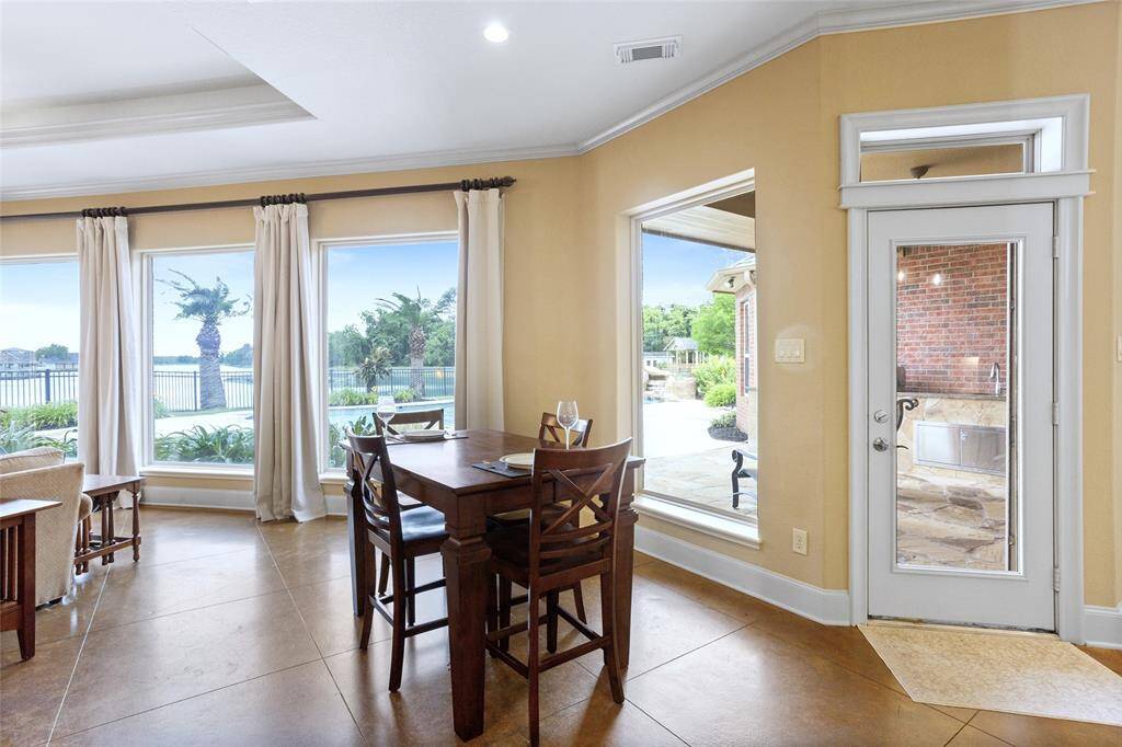 The bright breakfast nook is surrounded by large windows, offering a stunning view of the pool and lake. It seamlessly connects to an outdoor covered patio, creating the perfect setting for enjoying meals and entertaining guests.