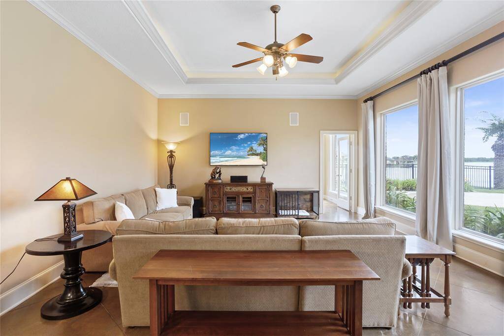 This bright and inviting family room features large windows that offer a lovely waterfront view. The uplit tray ceiling adds a touch of elegance, while the room is wired for sound, enhancing the overall ambiance for relaxation and entertainment.