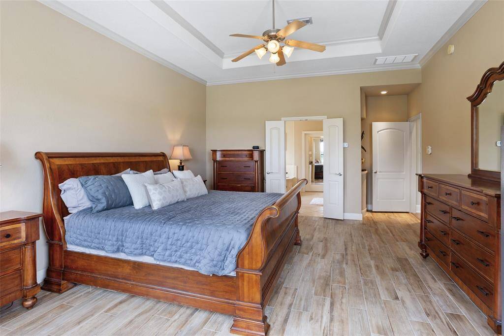 French doors open to the adjoining ensuite bathroom and oversized walk-in closet, offering a seamless transition between spaces for ultimate convenience and privacy.
