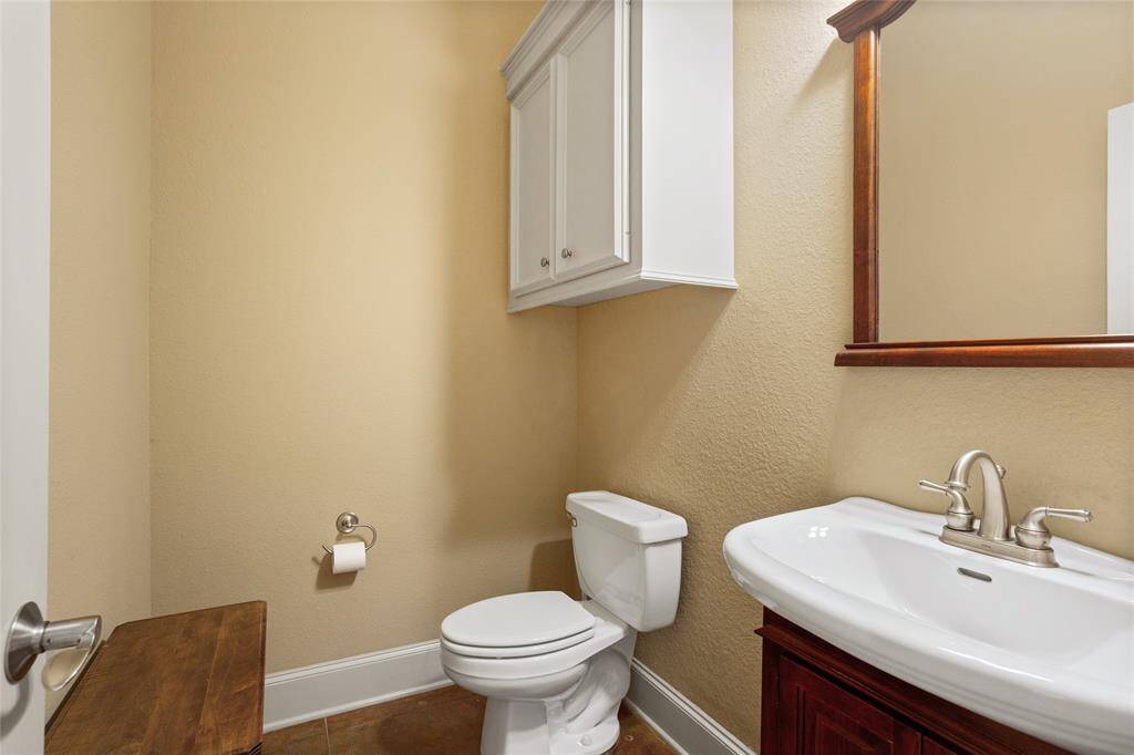 The guest powder room is thoughtfully designed with a wall-mounted cabinet for storage, a wooden-framed mirror, and stylish touches, providing a convenient and welcoming space for guests.