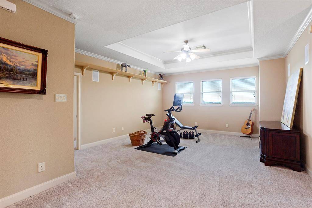 The versatile upstairs Gameroom is filled with natural light from three windows and features a tray ceiling, built-in shelving, crown molding, surround sound, and recessed lighting, creating an ideal space for relaxation or entertainment.
