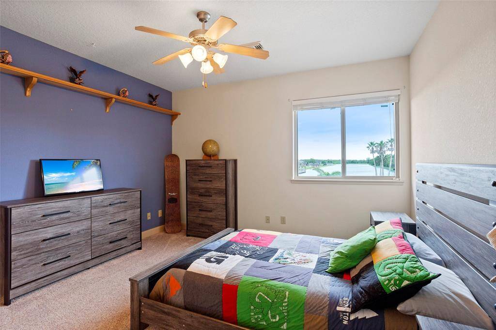 This bedroom features built-in shelving, an accent wall, a ceiling fan, and a walk-in closet. The window offers beautiful lake views, adding a serene touch to the space.