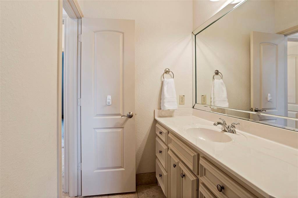 The upstairs Hollywood bathroom connects two upstairs bedrooms and features a long vanity with ample cabinet storage and a large mirror. Each bedroom enjoys its own private sink area, while sharing a central shower space for added convenience and functionality.