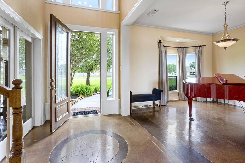 As you step through the front door, you’ll be greeted by soaring ceilings and the striking beauty of expertly stained concrete floors, creating an impressive and welcoming atmosphere.