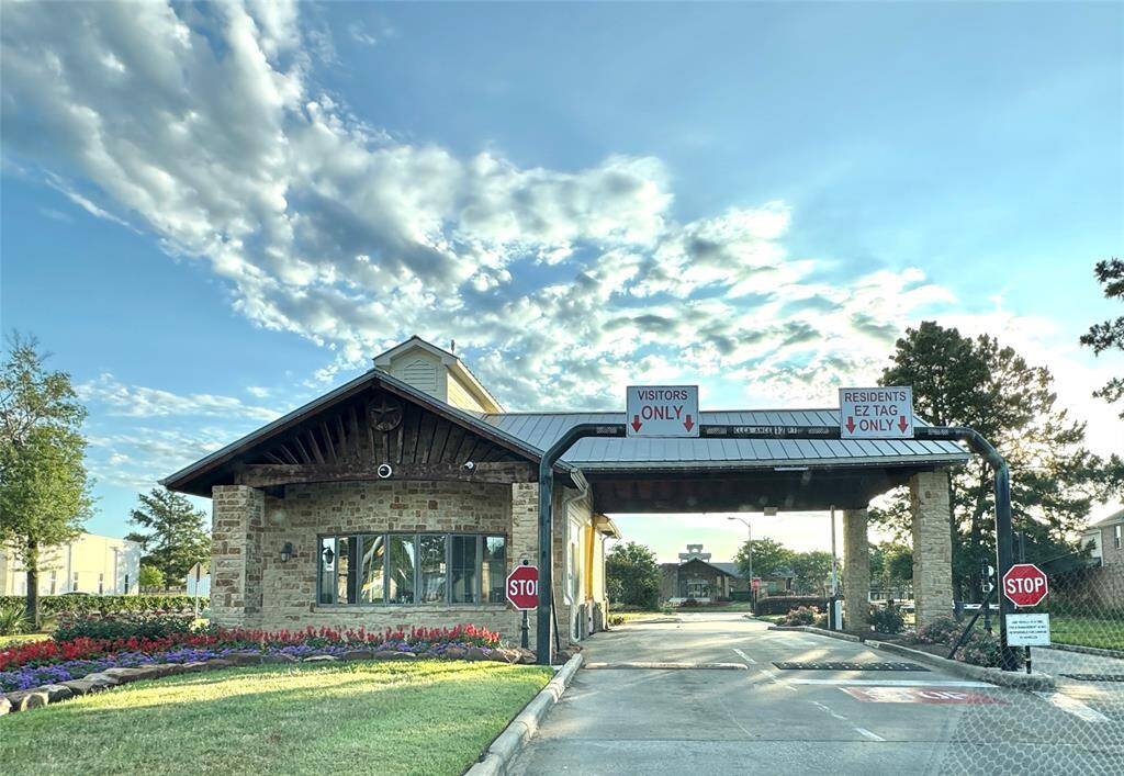 Manned/Gated community entrance with a stone guardhouse and separate lanes for visitors and residents.