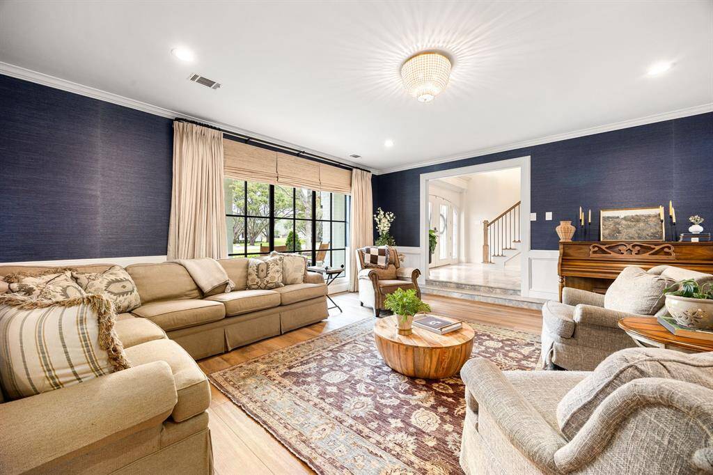 The inviting formal living room focuses on a cozy fireplace with an elegant white mantel complimented by richly wallpapered blue accent walls.  Your guests will enjoy a seamless flow into the living room. Perfect space for your bookclub gatherings or holiday events.