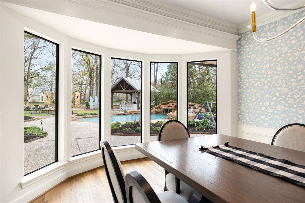 The formal dining room showcases elegant designer touches and breathtaking views of the backyard through recently replaced black-framed windows, adding a modern and sophisticated touch.