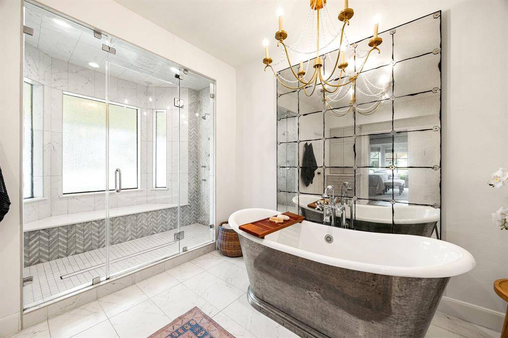 This extraordinary primary en-suite retreat features an imported stand-alone tub, a spacious double-sided shower, separate vanity areas, and a large walk-in closet with custom shelving, offering the perfect blend of luxury and functionality.