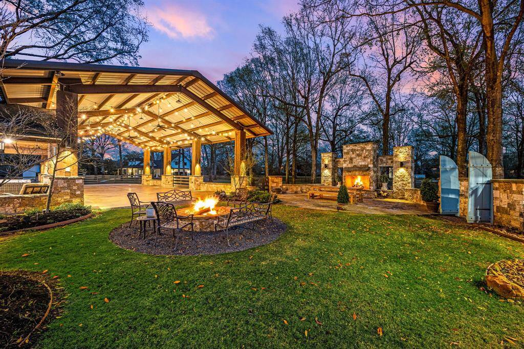 Imagine hosting an event in this charming pavilion-style space with string lights, a cozy fire pit surrounded by chairs, and an elegant stone fireplace.