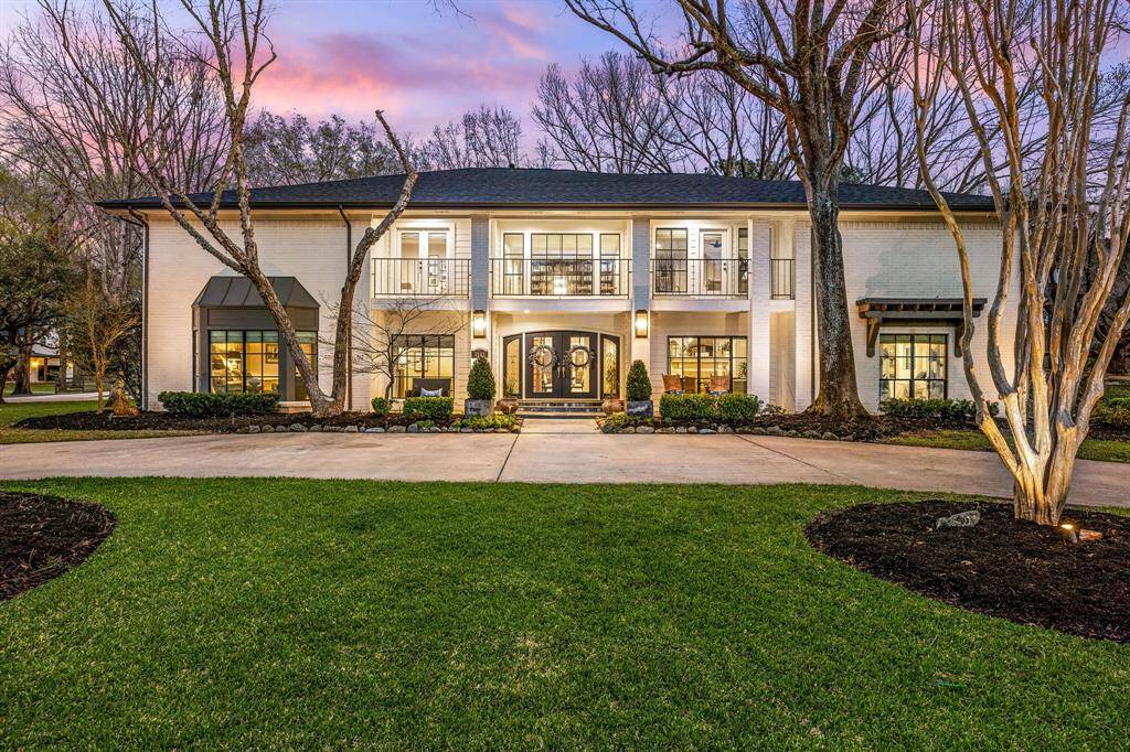 This stunning two-story, 5947 sq ft home features a classic brick façade and large windows. The expansive front lawn is beautifully landscaped, and complemented by a wide driveway and a welcoming entrance.