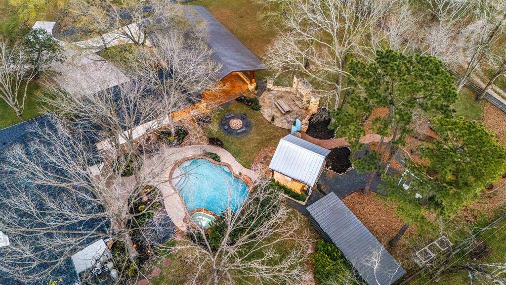 Aerial view of the back of the home. Here you can see the 3 stall barn area beyond the outdoor kitchen area.