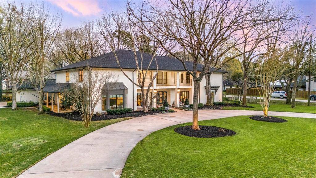 This beautiful two-story home features a classic design with large windows, a welcoming entry, and a circular driveway. It's set on a spacious, landscaped lot with mature trees, offering plenty of outdoor space and privacy.