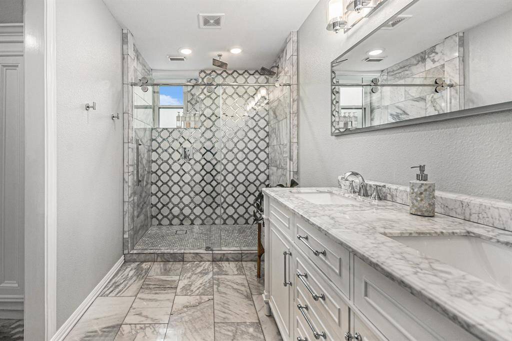 Primary Bathroom has a walk in shower and double sinks with marble.