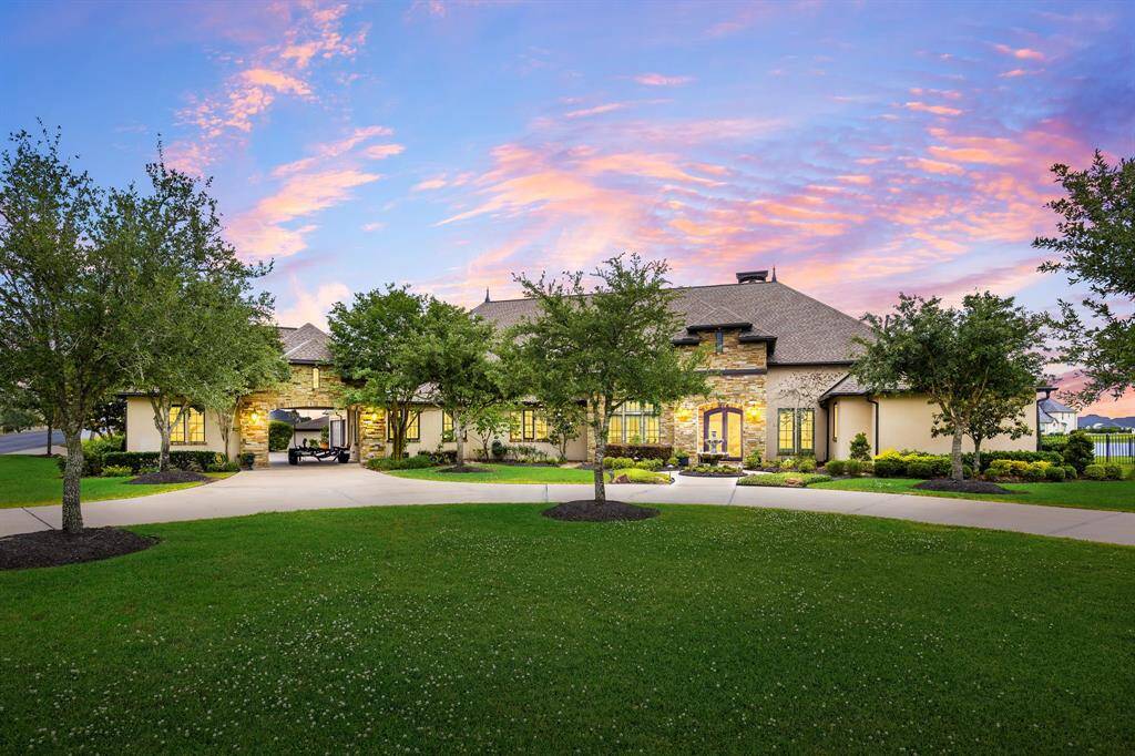 Experience resort-style living with a sparkling pool and stunning stone waterfall. The expansive covered patio is set against a backdrop of manicured landscaping and tranquil waterfront views.