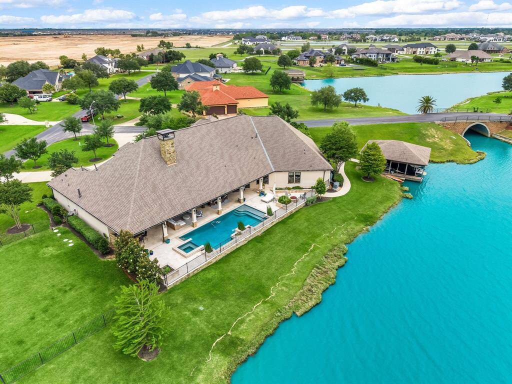 Expansive covered back patio with a walking path leading to a private boat dock. Enjoy direct boat access beneath the road to a second lake, offering even more opportunities for waterfront recreation.