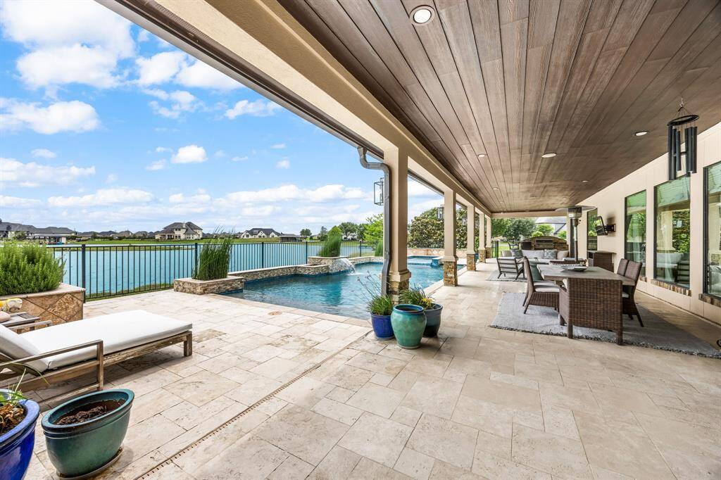 This outdoor space has a covered patio for lounging, a stylish spot for dining, and a gorgeous pool with peaceful lake views.