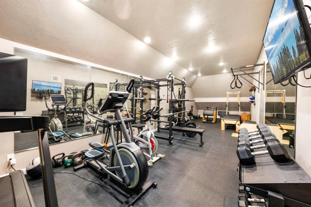 Spacious exercise room with mirrored walls situated above the 4-car garage. Optional weight equipment available for purchase.
