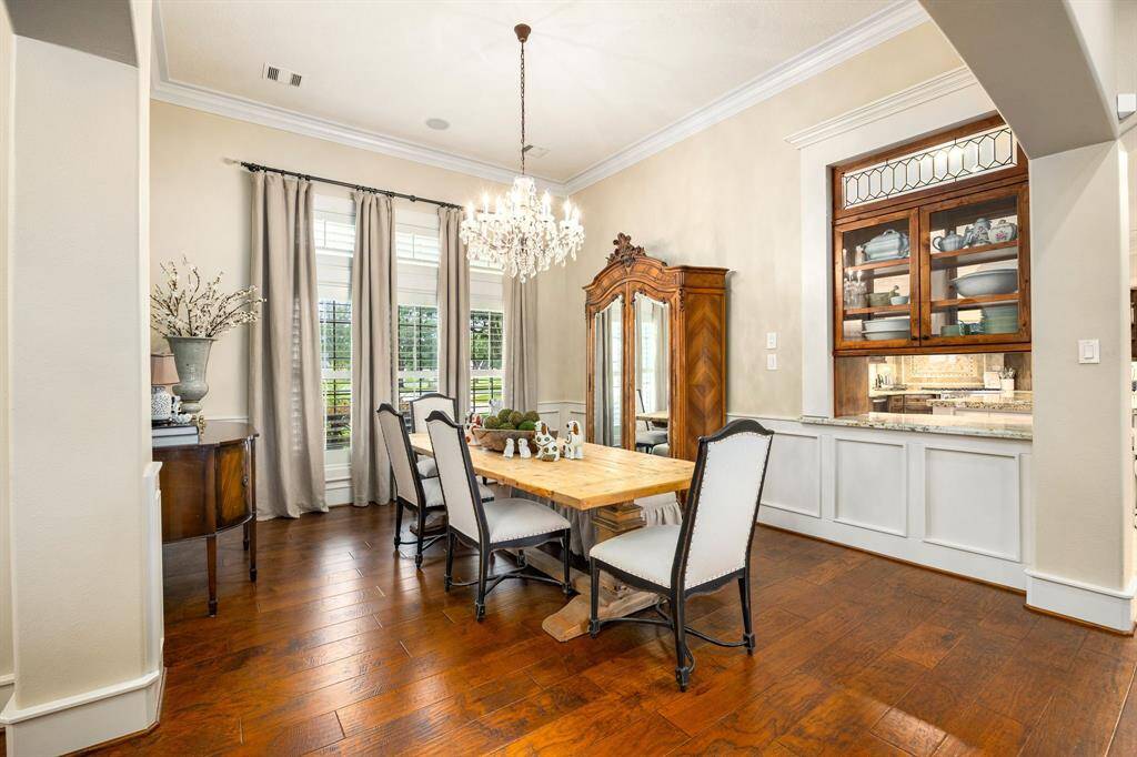 Elegant formal dining space with high ceilings, glass chandelier, custom window treatments and pass-through station into the kitchen. Custom shelves can store your favorite family heirlooms.
