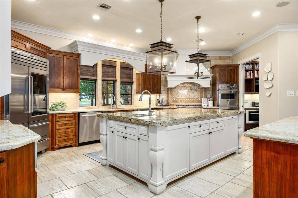 This beautifully crafted kitchen combines traditional elegance with modern functionality. Spacious island featuring detailed millwork, ample prep space, and a second sink.