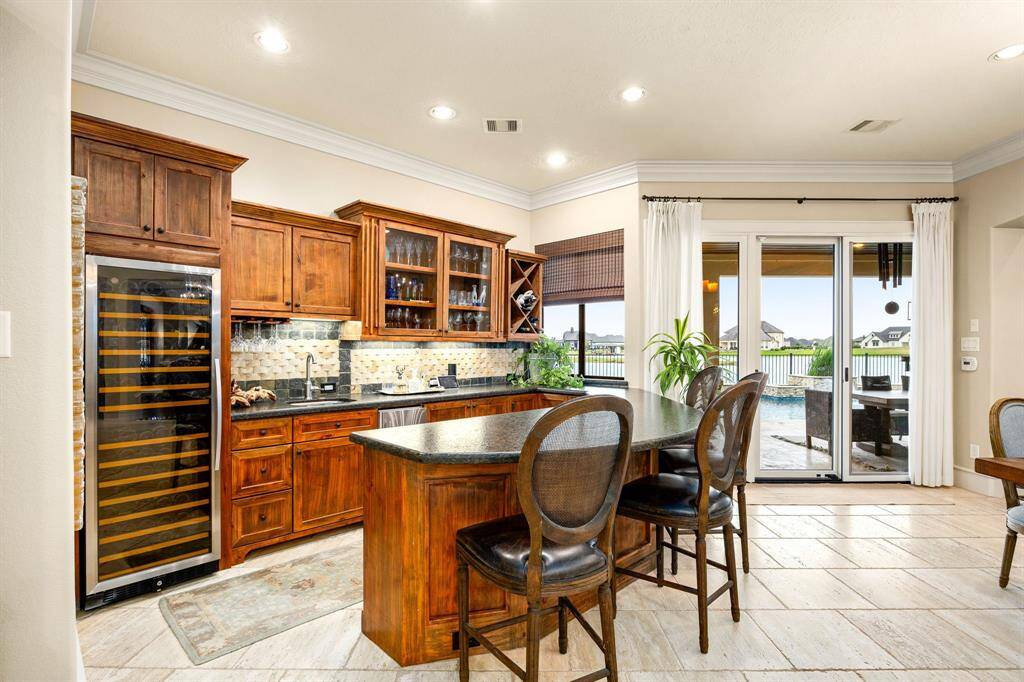 This custom bar area boasts leathered granite countertops and ample storage, complemented by a full-sized wine refrigerator and an ice maker. It's thoughtfully designed to meet all your entertaining needs, ensuring every gathering is a success.