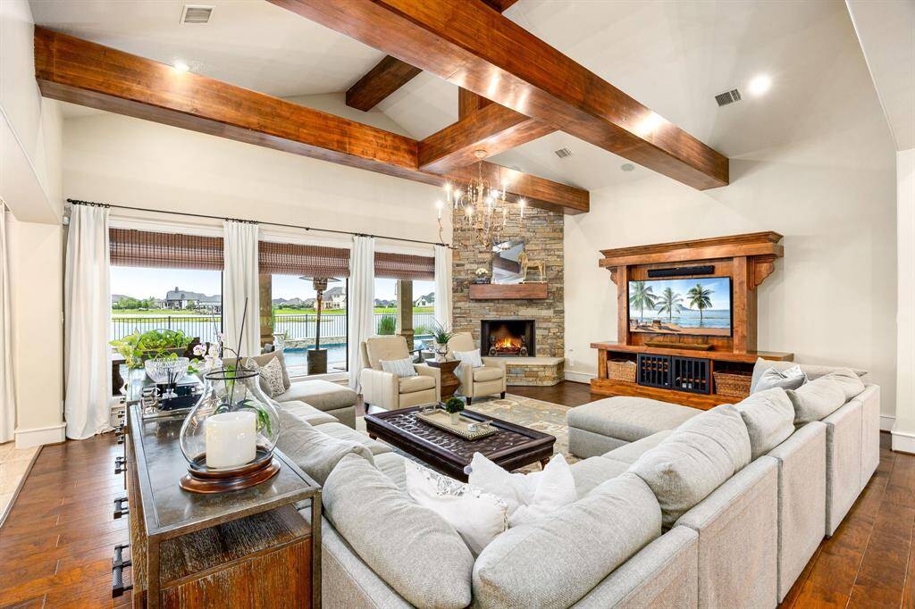 Living room boasts large wood beams and a cozy corner fireplace. The custom entertainment center is built in and will remain with the home. Windows have been trimmed out to add detail. Large sectional can be negotiated in the sale.