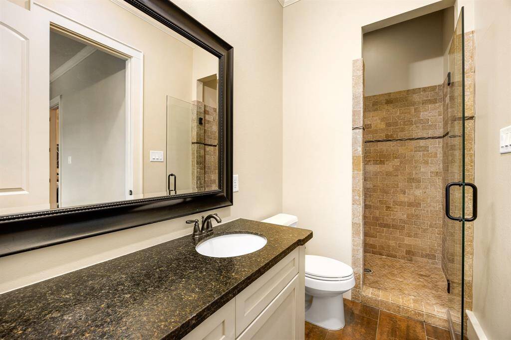 One of two secondary bathrooms featuring leathered granite countertops. Both secondary bedrooms offer separate sink areas, sharing a toilet and shower. The third bedroom includes its own en-suite bathroom for added privacy.